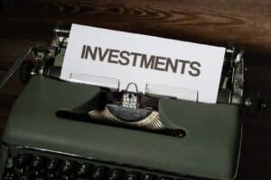 a close up of a typewriter with a paper that reads investments