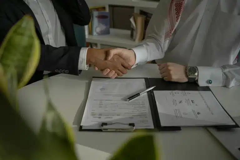 two people shaking hands over a piece of paper